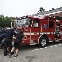 Fire Department Staff push a fire truck into the public safety complex during a push-in ceremony