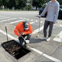 people testing water in a drain for mosquitos