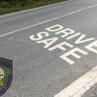 a photo of a road with the words "drive safe" in white road paint with the logo for the Exeter PD in the bottom left corner