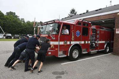 Fire Department Staff push a fire truck into the public safety complex during a push-in ceremony