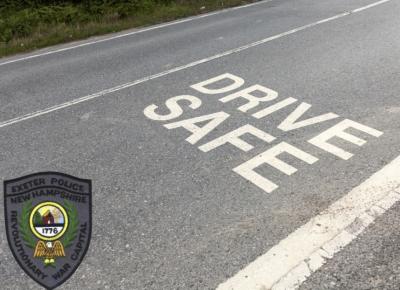 a photo of a road with the words "drive safe" in white road paint with the logo for the Exeter PD in the bottom left corner